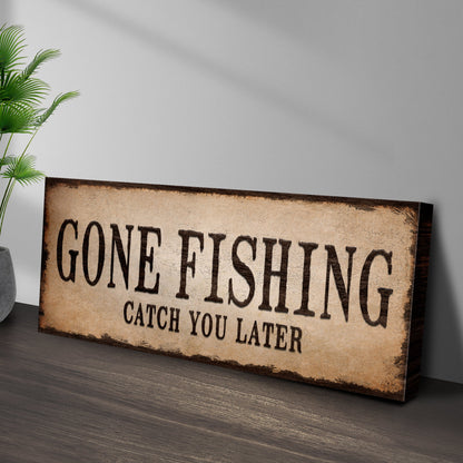 Gone Fishing Catch You Later canvas sign leaning against a gray wall on a dark wood floor