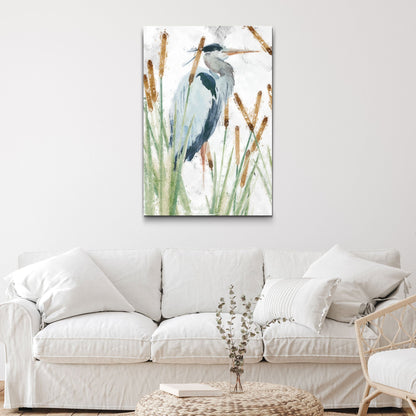 Tall canvas of a blue-gray heron standing among brown cattails and green reeds, hung above a white sofa