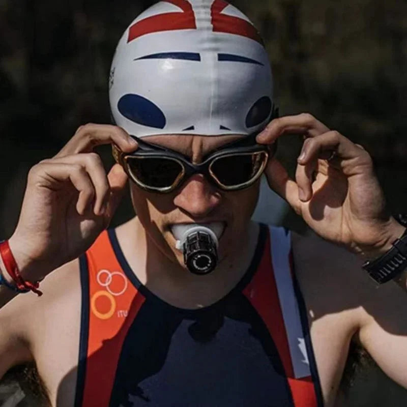 Triathlete wearing swimming cap and sunglasses using black breathing trainer device during outdoor endurance training