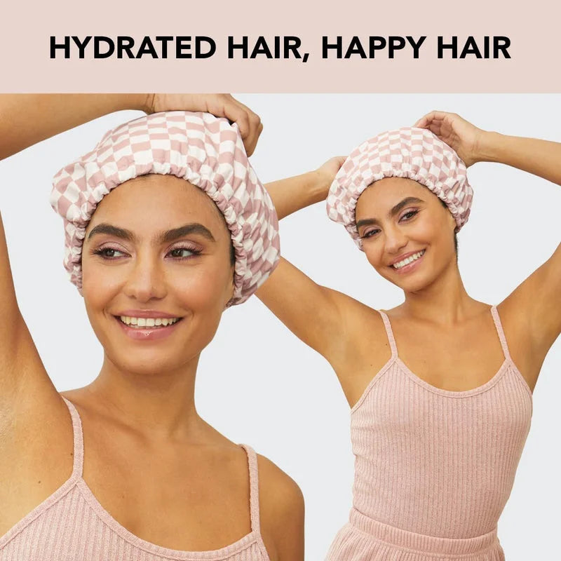 Two women wearing pink checkered shower caps demonstrating hydrated hair protection after shower
