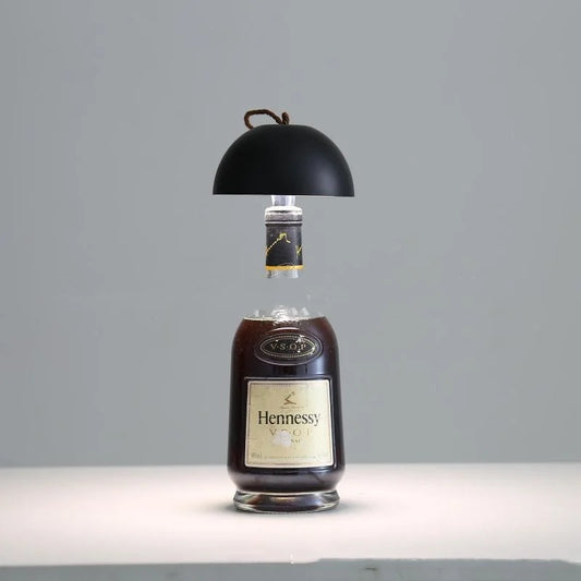Wine bottle table lamp with matte black dome shade and warm light glow
