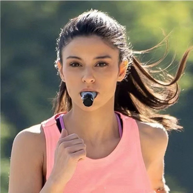 Woman in pink tank top using black breathing trainer mouthpiece during outdoor running exercise for respiratory training