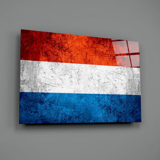 Weathered Netherlands flag glass wall art on a gray wall with a window reflection across the glossy glass