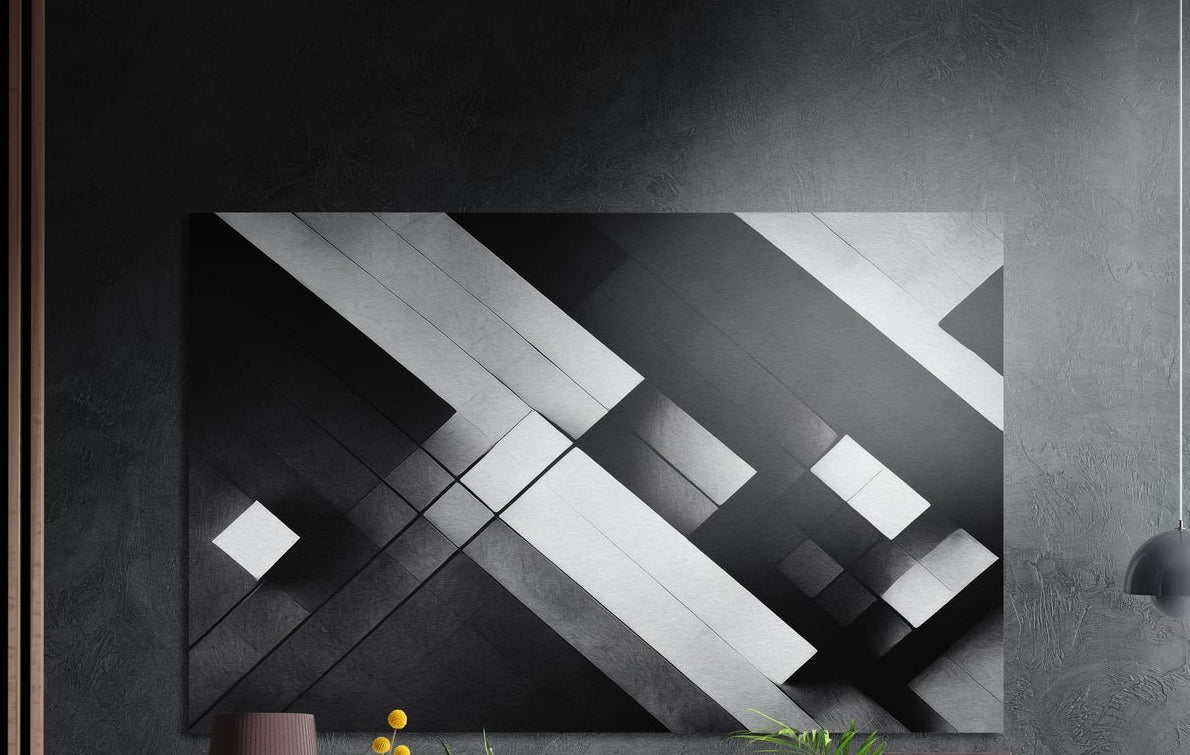 Black and white geometric diagonal bands, brushed aluminum wall art on a dark gray wall above a vase and yellow flowers