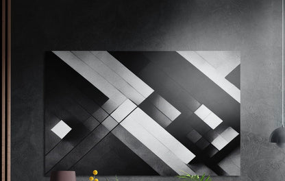 Black and white geometric diagonal bands, brushed aluminum wall art on a dark gray wall above a vase and yellow flowers