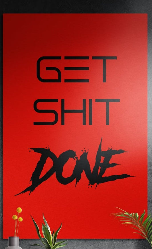 Red brush script Get Sh*t Done brushed aluminum wall art on a dark textured wall above potted plants
