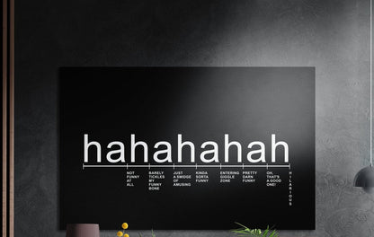 Laughter scale typography on black brushed aluminum wall art on a dark wall above a vase and plants