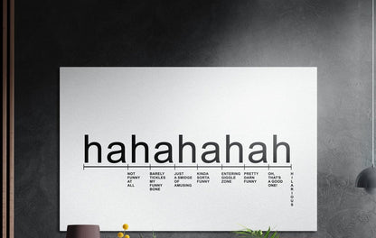 Hahaha laughter scale typography brushed aluminum wall art on a dark textured wall with plants below