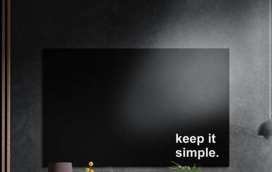 Keep it simple white text on black brushed aluminum wall art on a dark textured wall above potted plants