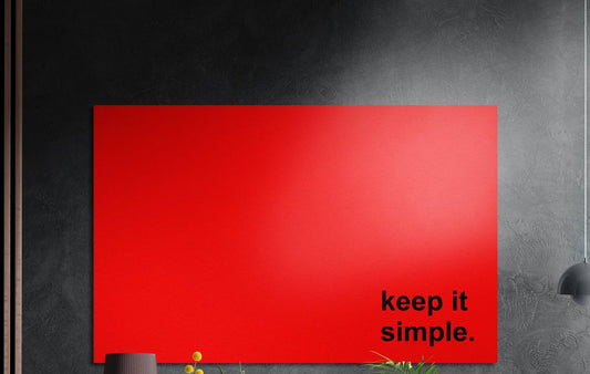 Keep it simple black text on red brushed aluminum wall art on a dark textured wall above potted plants