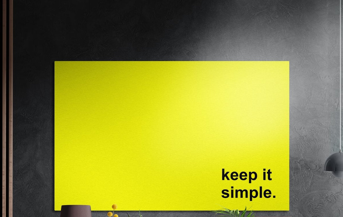 Keep it simple black text on yellow brushed aluminum wall art on a dark textured wall above potted plants