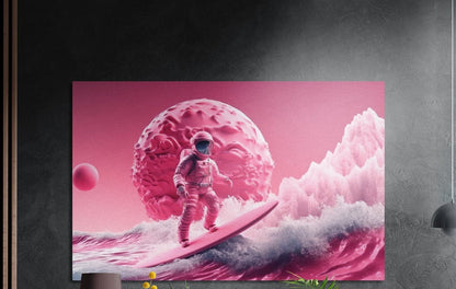 Pink astronaut surfing a foaming wave below a pink planet, brushed aluminum wall art on a dark wall above a sideboard