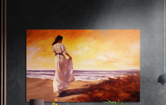 Woman in a long white dress walking a sunset beach under an orange sky, brushed aluminum wall art above a sideboard