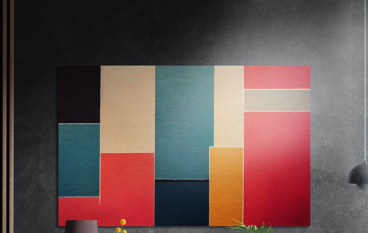 Red, teal and mustard color block abstract brushed aluminum wall art on a dark gray wall above a vase and yellow flowers