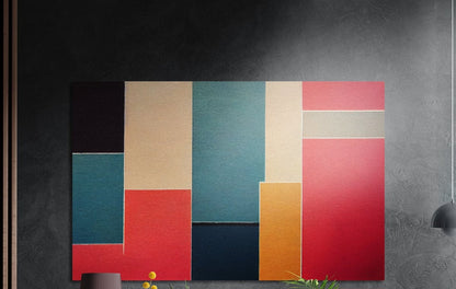 Red, teal and mustard color block abstract brushed aluminum wall art on a dark gray wall above a vase and yellow flowers