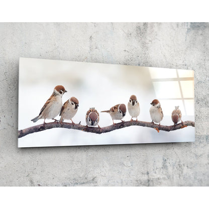 Seven sparrows on a bare branch glass wall art angled on a pale concrete wall