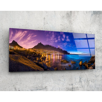 Coastal town at dusk panoramic glass wall art shown at an angle on a concrete wall