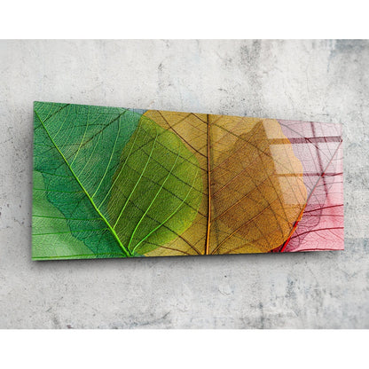 Green to pink veined leaves panoramic glass wall art on a pale concrete wall, seen at an angle