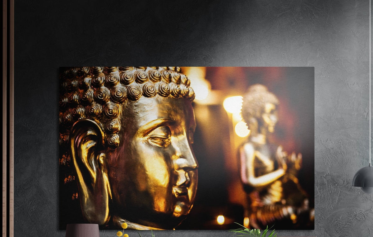 Golden Buddha face close up brushed aluminum wall art on a dark gray wall above a mauve lamp and plants
