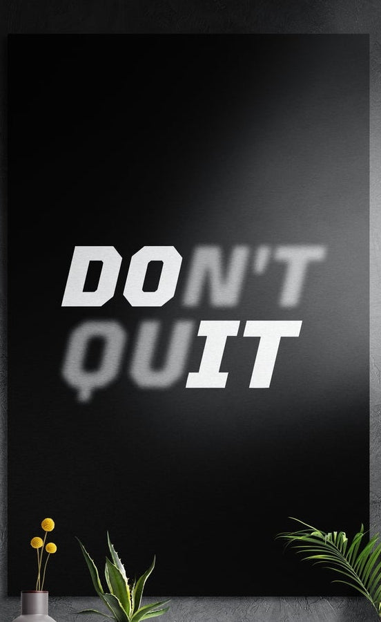 Do it bold white text on black brushed aluminum wall art on a gray wall above a vase of yellow flowers