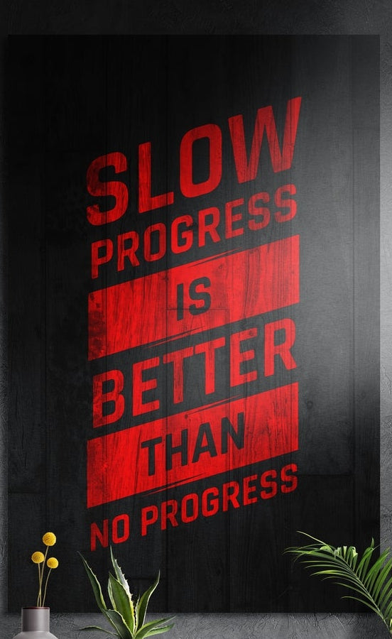 Red motivational lettering on dark wood grain, brushed aluminum wall art on a dark gray wall above yellow flowers