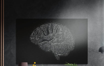 Binary code brain on black brushed aluminum wall art on a dark wall above a vase and plants