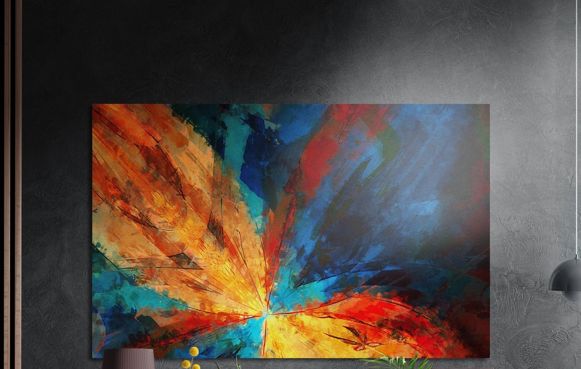 Fiery abstract flower burst in orange and turquoise, brushed aluminum wall art on a dark gray wall beside a black lamp