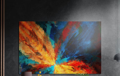 Fiery abstract flower burst in orange and turquoise, brushed aluminum wall art on a dark gray wall beside a black lamp