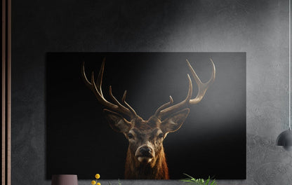 Antlered stag portrait brushed aluminum wall art on a dark wall above a sideboard with yellow flowers