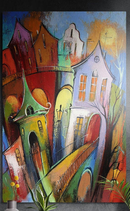 Whimsical colorful leaning houses brushed aluminum wall art on a dark textured wall above potted plants