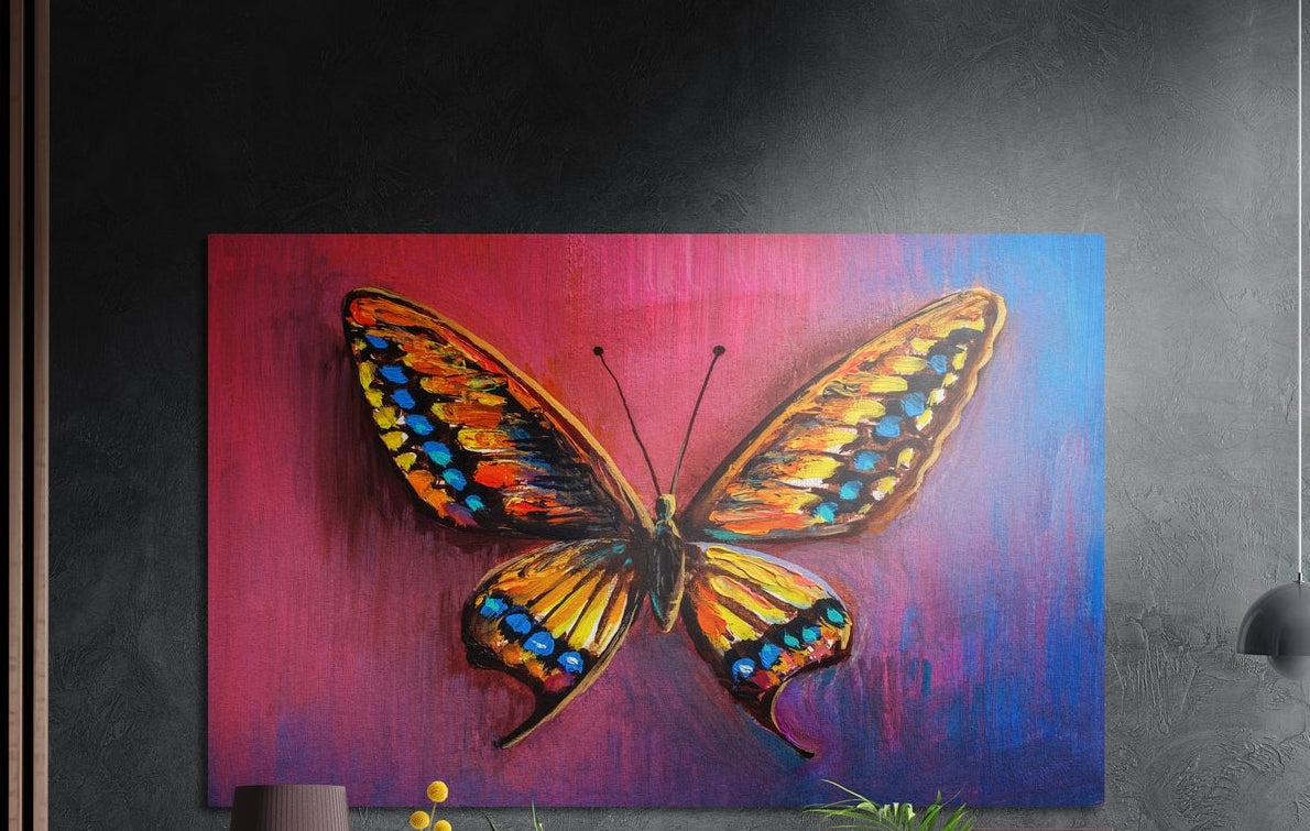 Orange butterfly on a pink and blue background, brushed aluminum wall art on a gray wall above a vase and a plant
