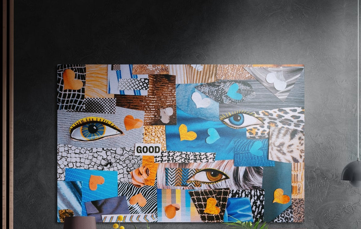 Blue paper collage eyes and hearts brushed aluminum wall art on a dark textured wall above a lamp, flowers and plants