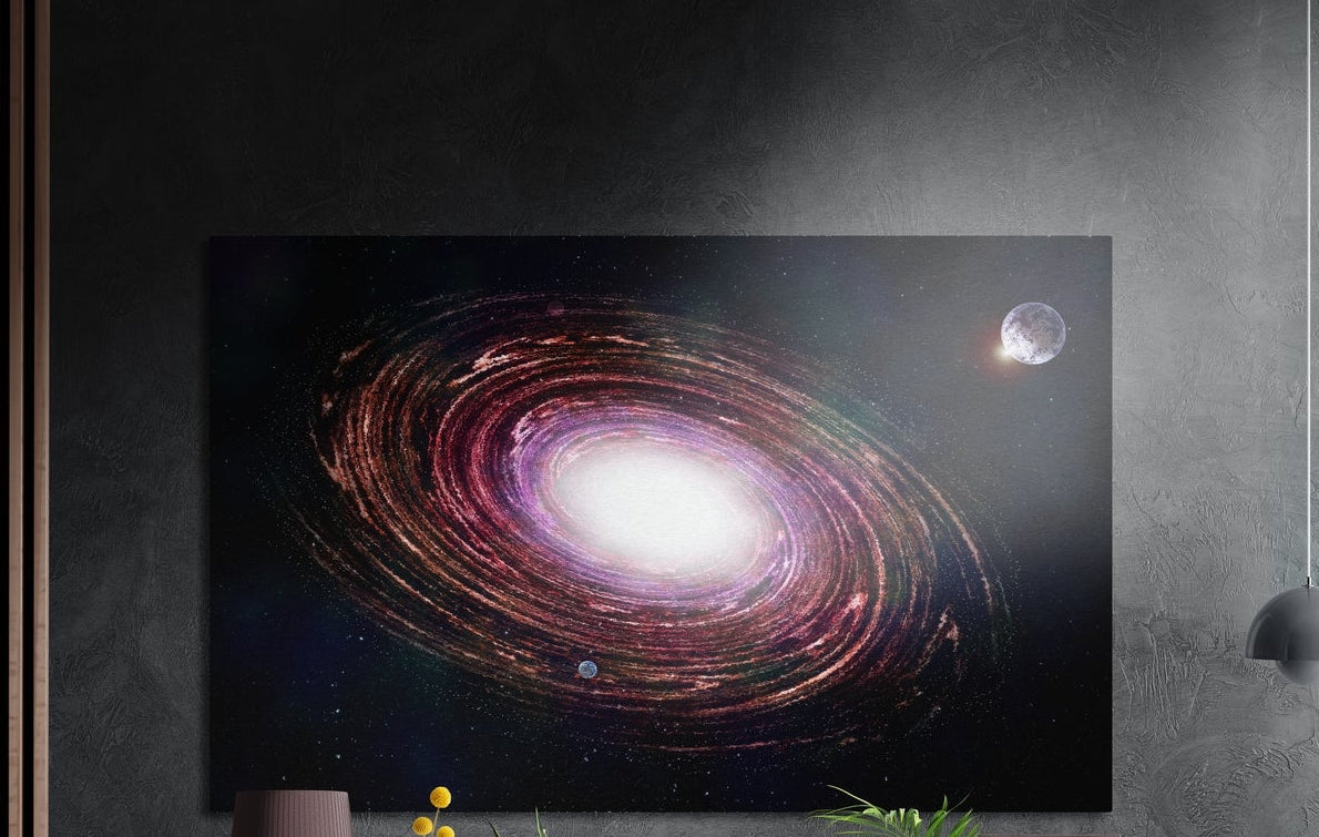Spiral galaxy and distant moon brushed aluminum wall art on a dark gray wall above a mauve lamp and plants