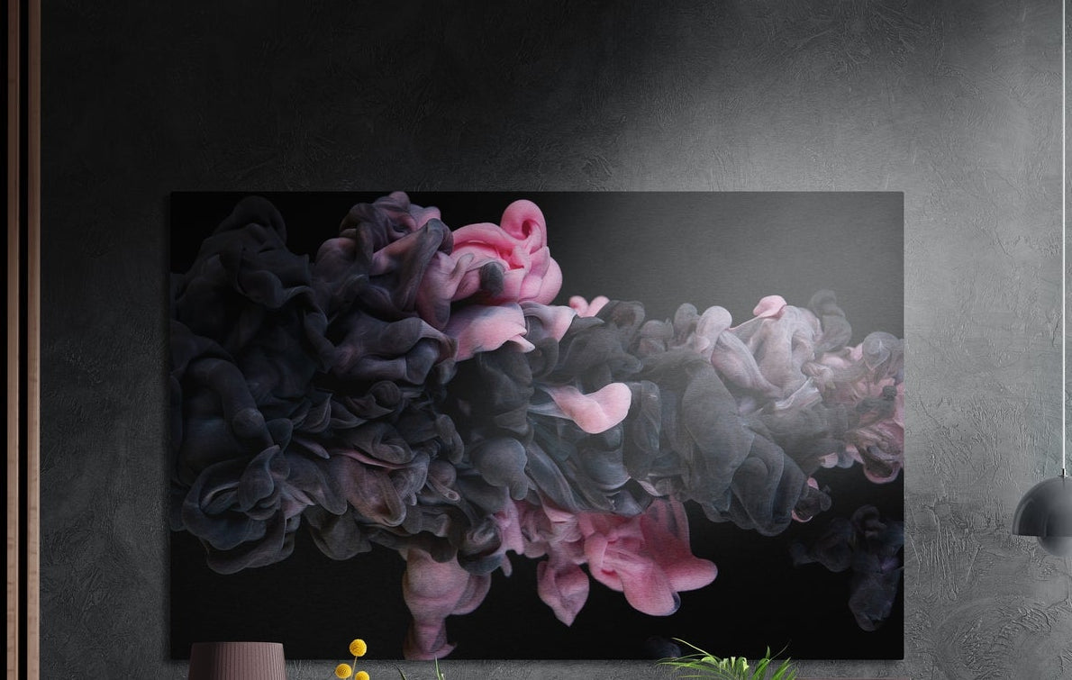 Pink and charcoal ink cloud brushed aluminum wall art on a dark textured wall above a vase and plants