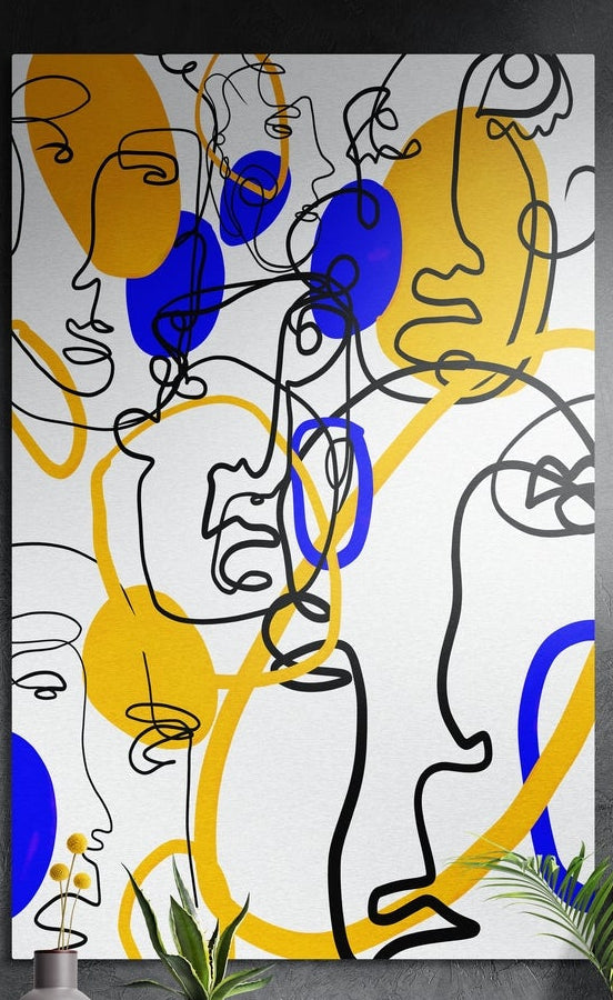 Black line drawn faces with blue and yellow shapes on white, brushed aluminum wall art on a dark wall above a vase and leaves