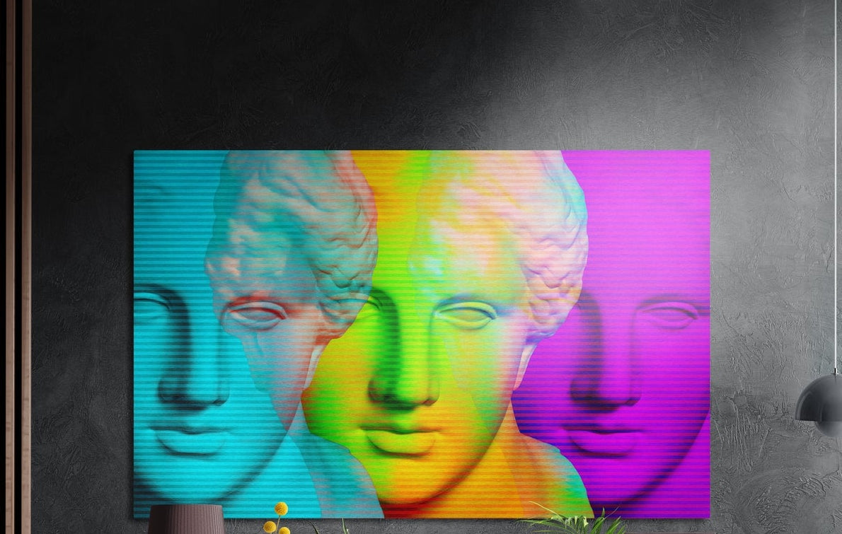 Rainbow neon classical bust faces brushed aluminum wall art on a dark gray wall above yellow flowers