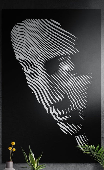 Black and white striped line face brushed aluminum wall art hung on a dark textured wall above potted plants