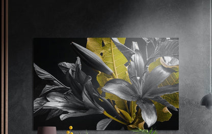 Monochrome lilies with golden leaves brushed aluminum wall art on a dark textured wall beside wood slats and a lamp