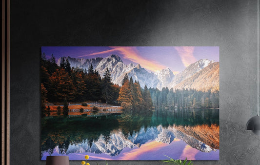 Snowy peaks mirror lake brushed aluminum wall art on a dark gray wall above a sideboard with a vase and plants