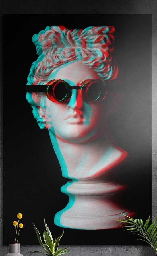 Red and teal glitch bust in sunglasses brushed aluminum wall art on a gray wall above yellow flowers and plants