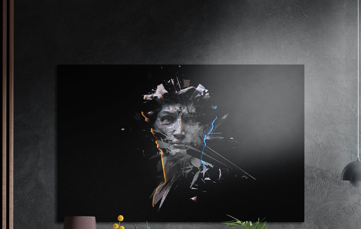 Shattered classical statue head brushed aluminum wall art on a dark wall above the tips of potted plants