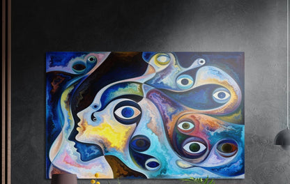 Swirling blue and yellow abstract faces and eyes, brushed aluminum wall art on a dark textured wall by wood slats