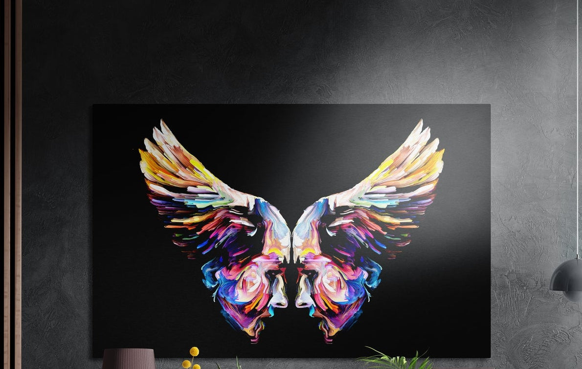 Rainbow wings made of two mirrored painted faces on black, brushed aluminum wall art above a wooden sideboard
