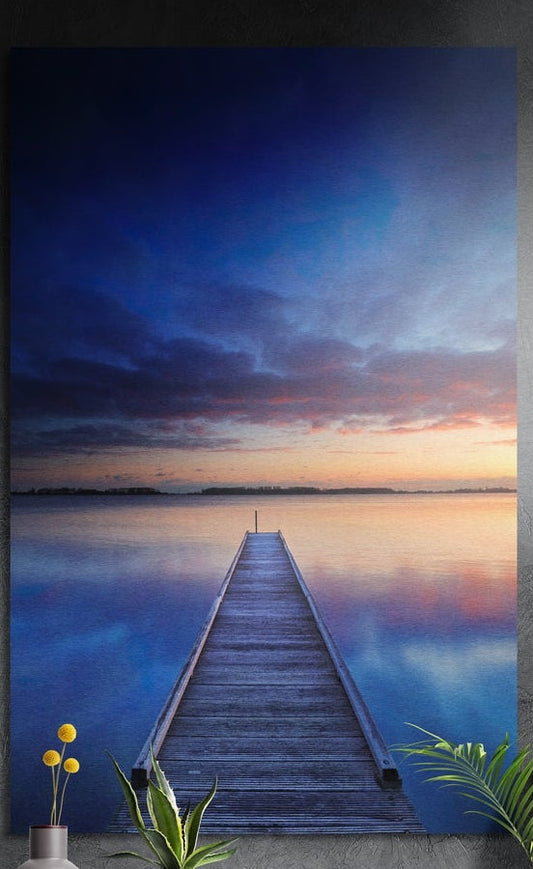 Wooden pier on a calm lake at dusk brushed aluminum wall art on a dark textured wall behind a vase and plants