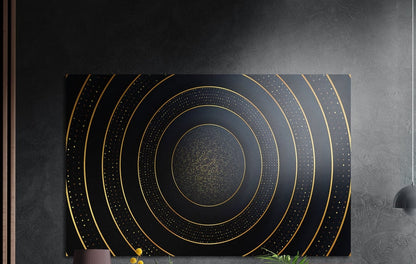 Gold rings on black abstract brushed aluminum wall art on a dark wall above the tips of potted plants