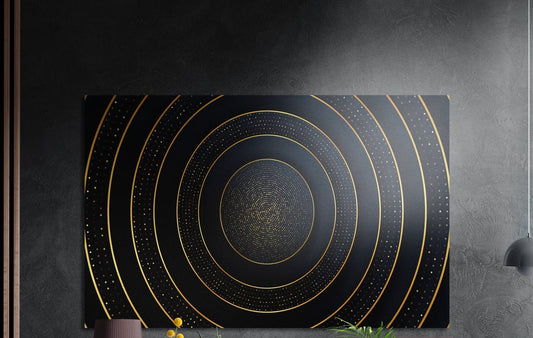 Gold rings on black abstract brushed aluminum wall art on a dark wall above the tips of potted plants