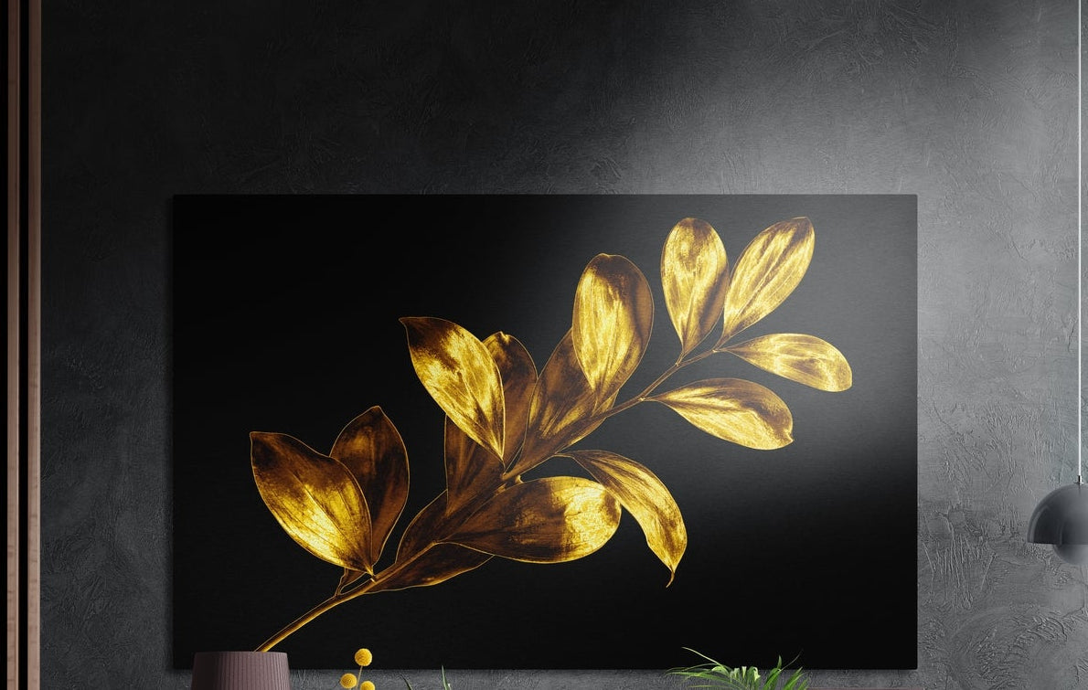 Golden leaves branch on black, brushed aluminum wall art on a dark gray wall beside a black wall lamp