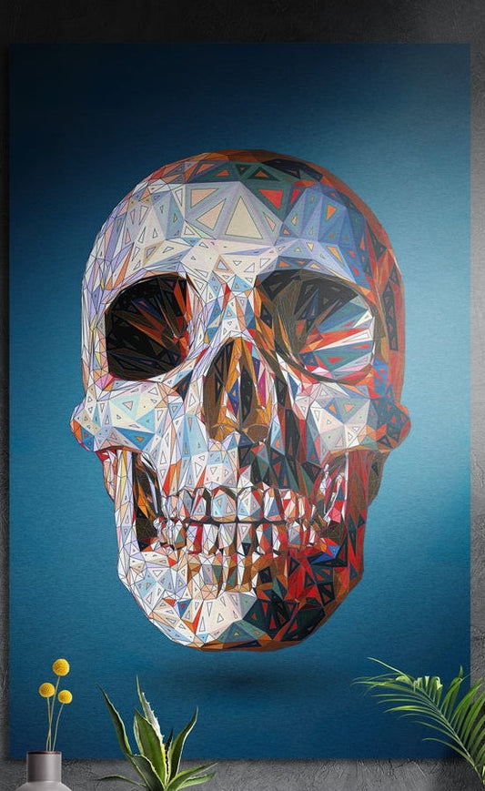 Geometric crystal skull on blue brushed aluminum wall art on a gray concrete wall above small plants