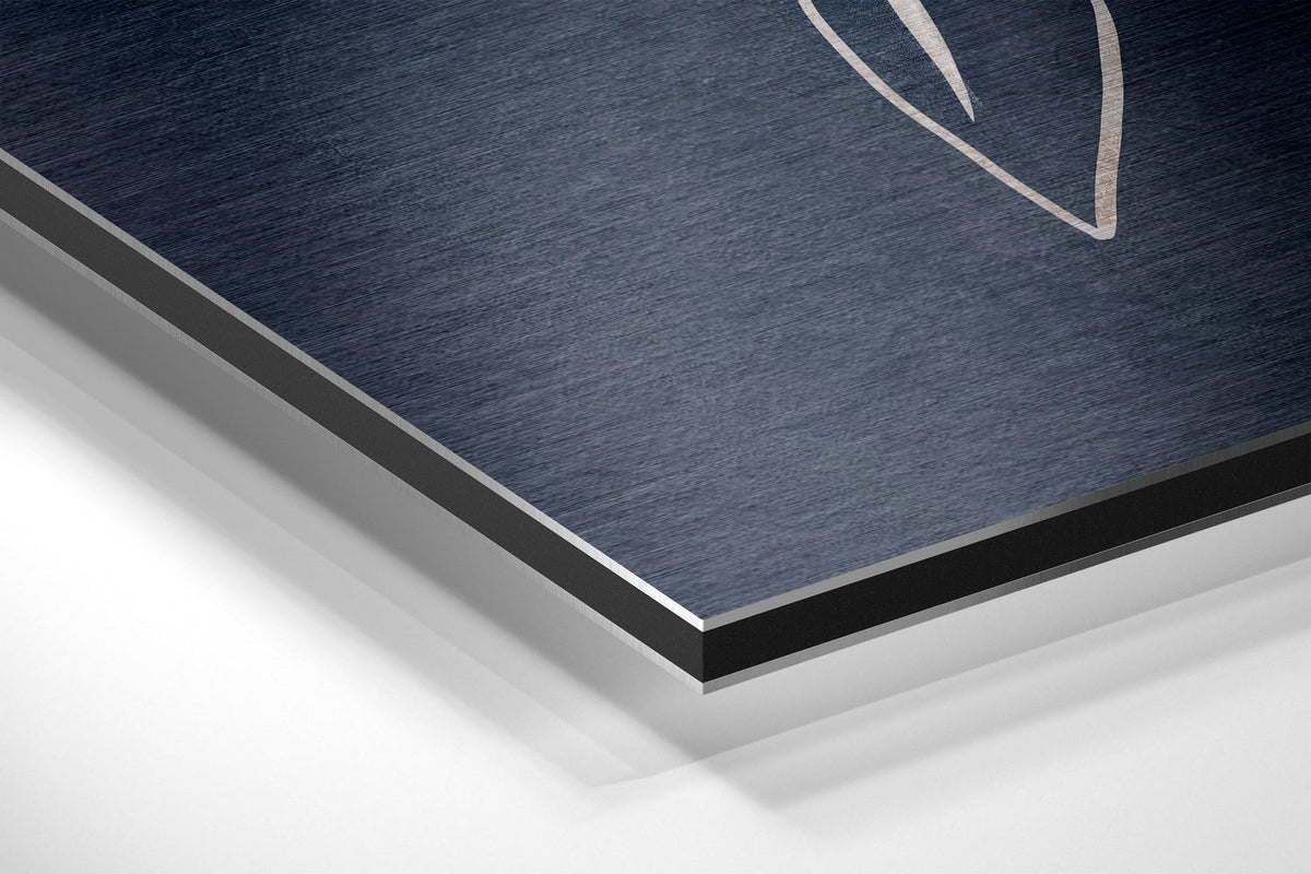 White flower on navy and blush brushed aluminum panel corner close-up showing the brushed metal grain