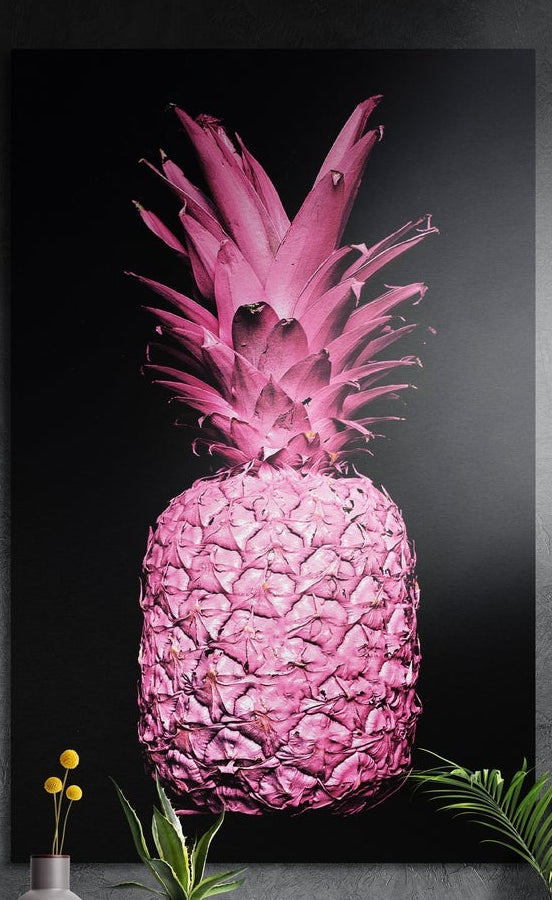 Hot pink pineapple on a black background, brushed aluminum wall art above a wooden sideboard with plants